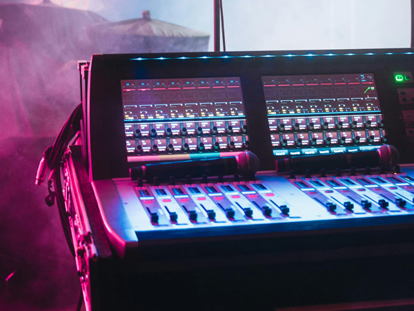 Eine Aufnahme eines Mischpults im Liveeinsatz auf einer Bühne.