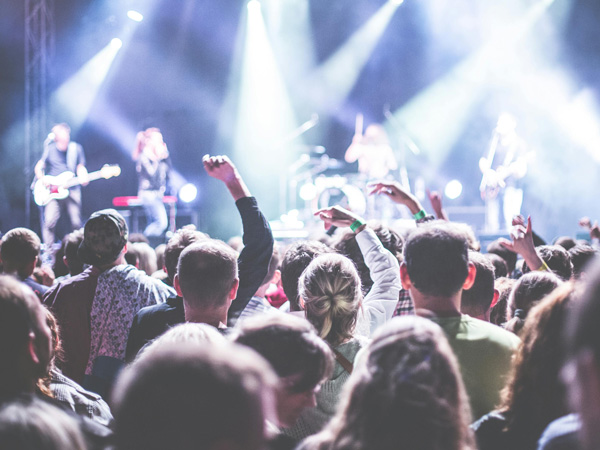 Ein Konzertpublikum jubelt vor einer Liveband.
